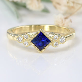 Princess cut blue sapphire and diamond cluster ring in 18ct gold.