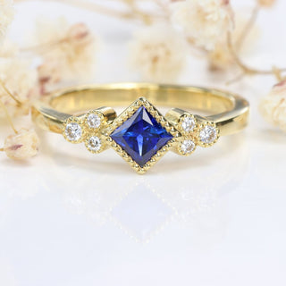 Princess cut blue sapphire and diamond ring with white flowers.