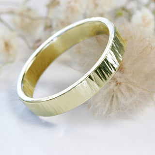 A gold treebark texture ring posed on a flower