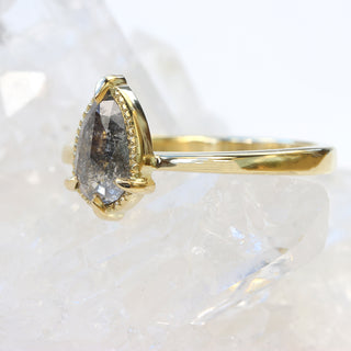 Side view of 18ct gold pear cut salt and pepper diamond engagement ring on quartz crystal.