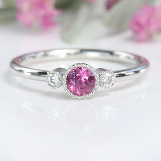 Detailed close-up of petite pink sapphire and Canadian diamonds in milgrain settings.