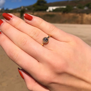 Salt and pepper diamond solitaire ring in 18ct gold shown worn on hand outdoors.