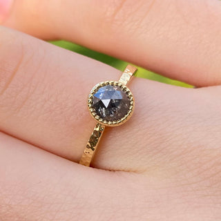 Closeup on hand of salt and pepper solitaire engagement ring in 18ct gold