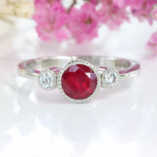 Ruby and diamond trilogy ring in platinum with pink flowers in the background.