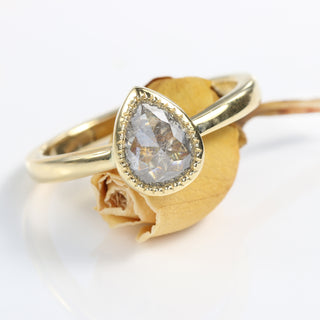 Pear cut salt and pepper diamond solitaire ring on orange rose bud